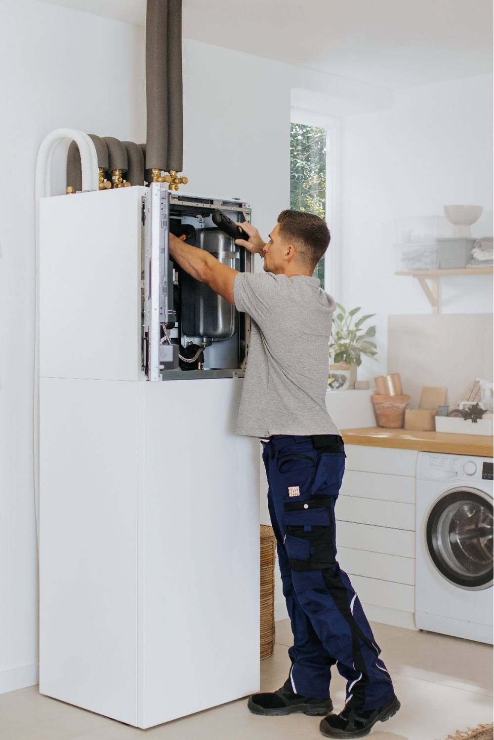 Installateur werkt aan het binnendeel van een warmtepompsysteem in een wasruimte