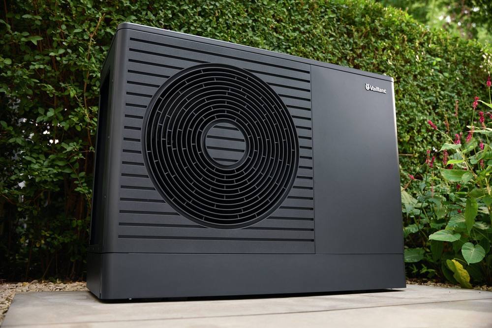 Vaillant aroTHERM plus van dichtbij, op een terras voor een groene haag