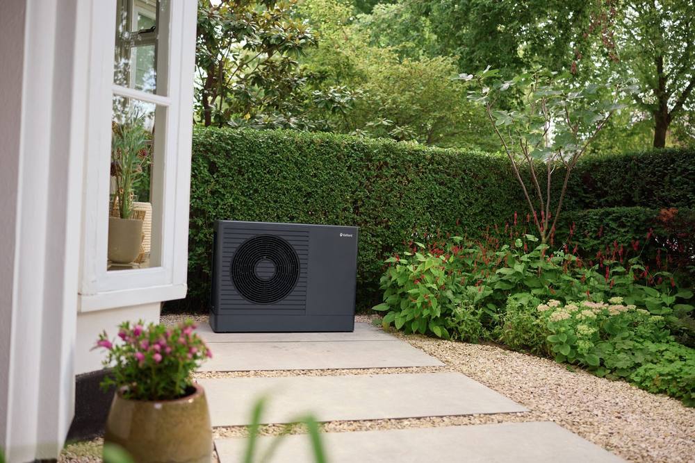 Vaillant warmtepomp achter in een tuin, aan het eind van een tegelpad