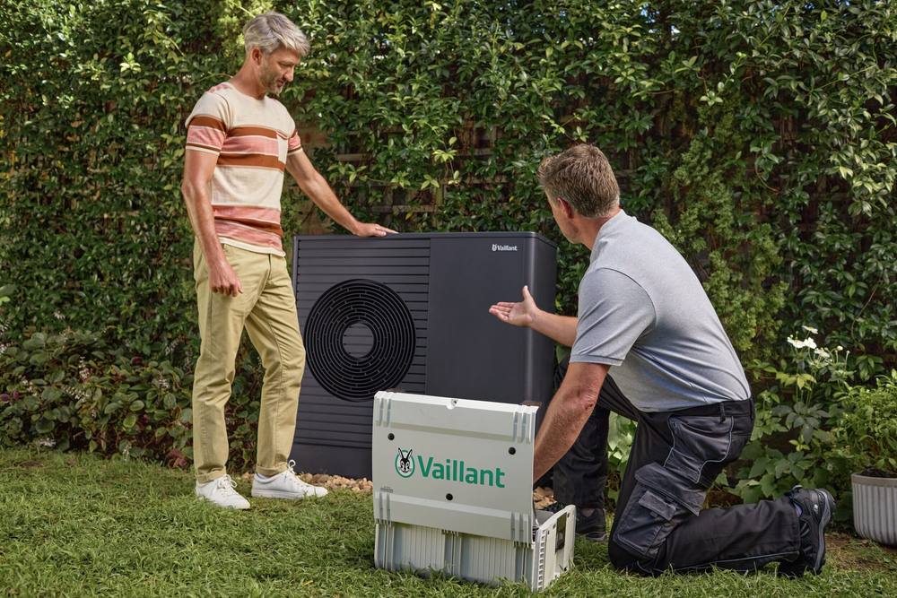 Installateur legt een bewoner de nieuwe Vaillant warmtepomp in de tuin uit